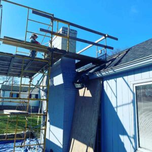 Chimney rebuild in progress with technician working while standing on scaffolding