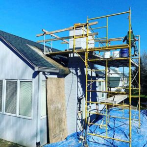 Side view of Chimney rebuild in progress with technician working while standing on scaffolding